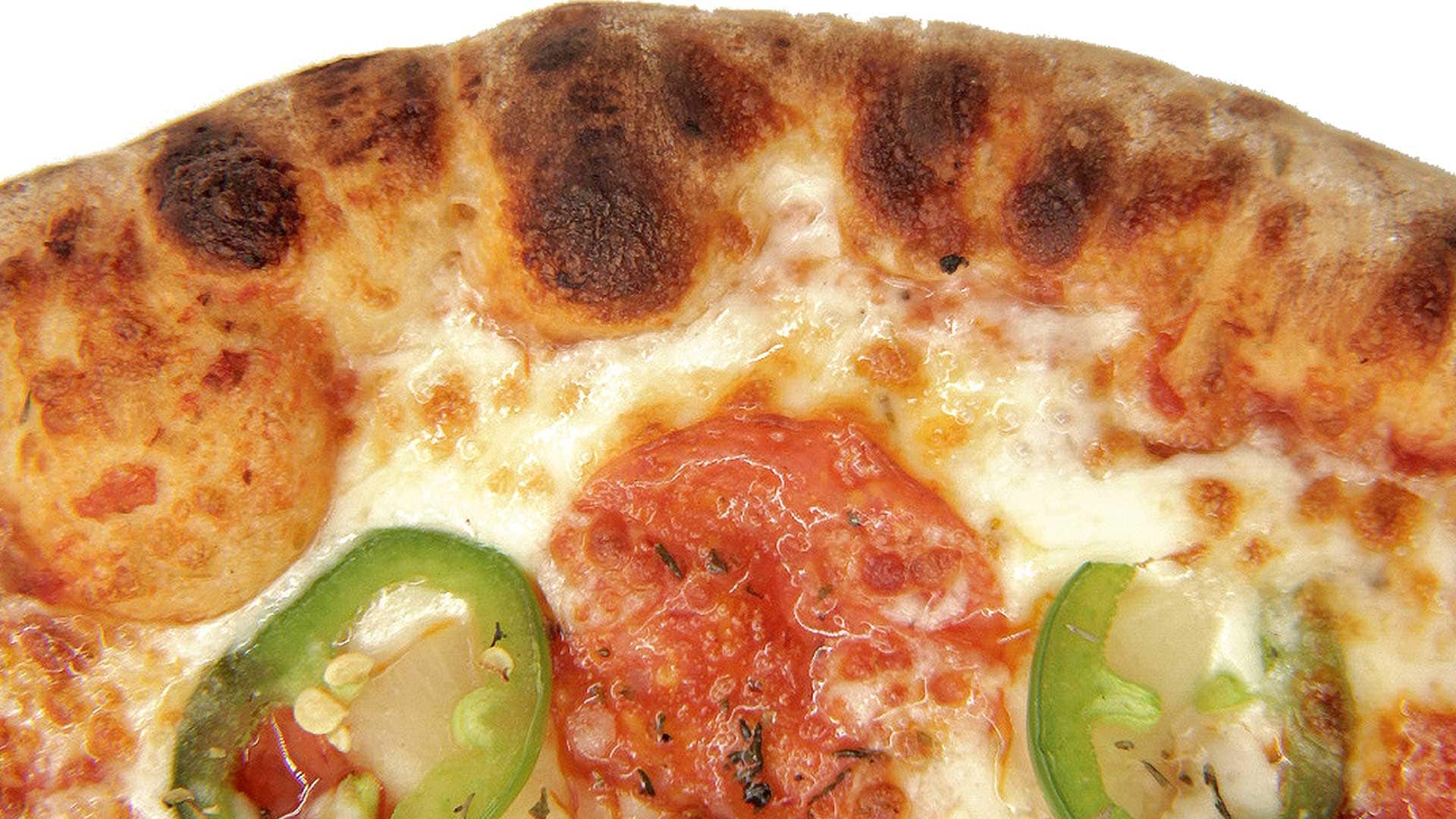 Freshly baked pizza with melted cheese, tomato slices, green peppers, and a crispy crust, showcasing delicious and quality dairy ingredients from Burnett Dairy Cooperative for foodservice.
