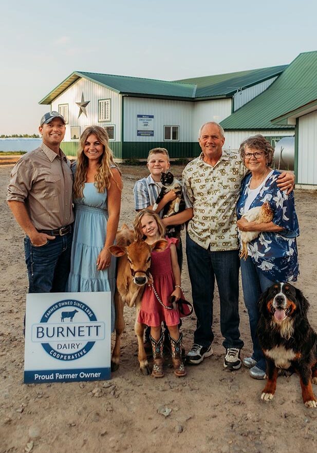 Farmers and family members standing in front of Burnett Dairy Cooperative building, showcasing dairy farming and foodservice industry involvement.